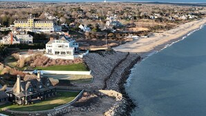 A coastal property with a large house, a smaller white house, and a stone retaining wall along the beach. - The Saltbox - Watch Hill's Award-Winning Waterfront Retreat.  (Westerly)