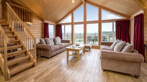 A spacious wooden interior with a high ceiling, large windows, and a staircase. - The Buchanan - sleeps 6 guests  in 3 bedrooms with hot tub - 5 star award winning lodges (Lauder)