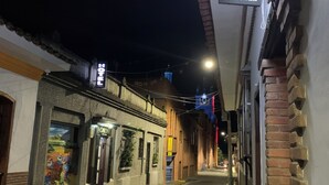 A narrow street with a hotel named "Hotel Don Juan" on the right. There are buildings on both sides of the street, and a mural is visible on the left. - HOTEL DON JUAN  (Guadalajara de Buga)