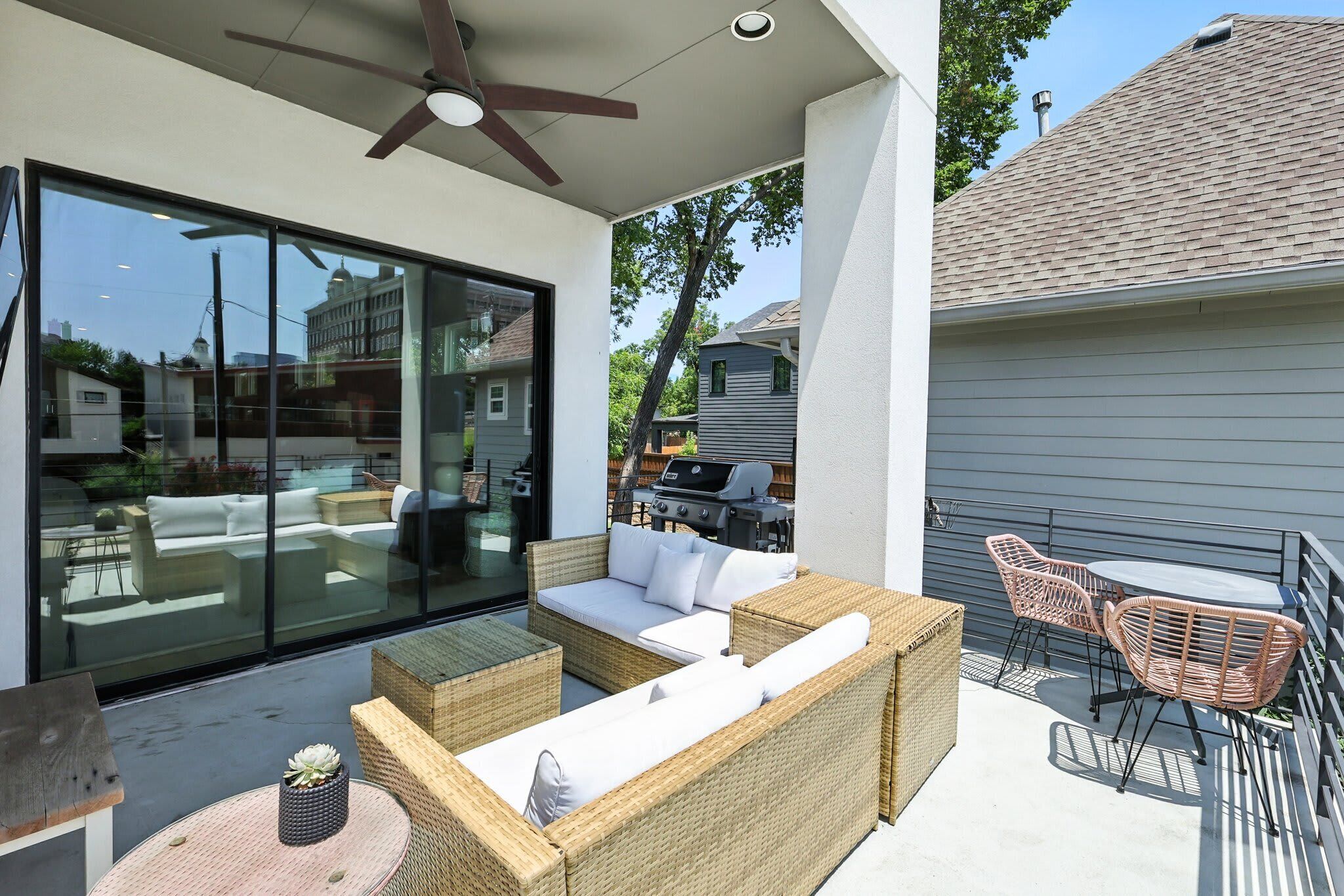 A covered patio with wicker furniture, a ceiling fan, and a view of neighboring houses.