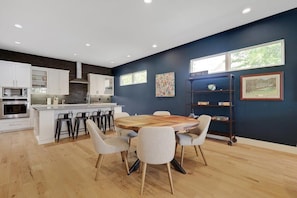 Una cocina moderna con armarios blancos, una mesa de comedor de madera y taburetes de bar.