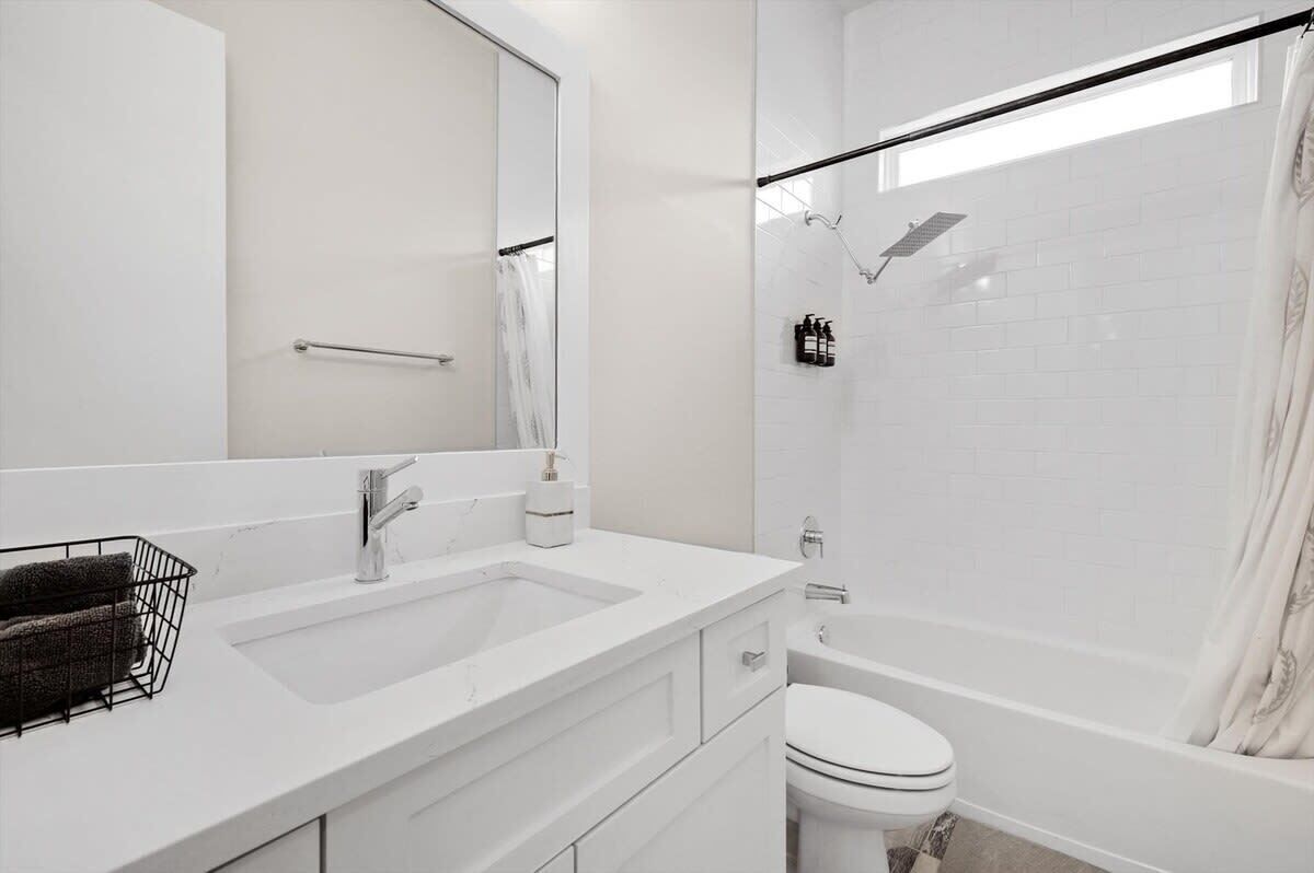 A modern bathroom with a white sink, mirror, and toilet.