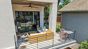 A modern balcony with wicker furniture, a grill, and a view of the backyard. - Modern Luxury Townhouse | Uptown & Attractions (Dallas)