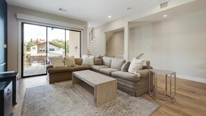 A modern living room with a sectional sofa, a coffee table, and a small side table. - Modern Luxury Townhouse | Uptown & Attractions (Dallas)