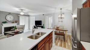 A modern kitchen with a large island, stainless steel appliances, and a dining area with a wooden table and chairs. - Heart of Dallas - Cozy Apt, 2Bed, Pool (30+ days) (Dallas)