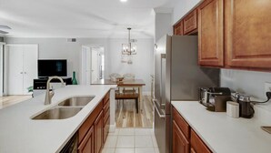 A modern kitchen with a large island, stainless steel appliances, and wooden cabinets. - Heart of Dallas - Cozy Apt, 2Bed, Pool (30+ days) (Dallas)