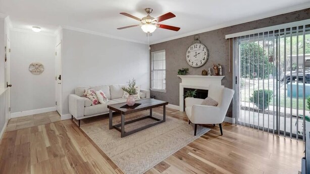 A living room with a white sofa, a coffee table, a white armchair, a fireplace, and a large window with a view of a swimming pool. - Heart of Dallas - Cozy Apt, 2Bed, Pool (30+ days) (Dallas)