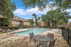 A swimming pool with lounge chairs and tables, surrounded by buildings and trees. - Heart of Dallas - Cozy Apt, 2Bed, Pool (30+ days) (Dallas)