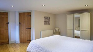 A bedroom with a large bed, wooden doors, a radiator, and a mirror in the closet. - Host & Stay | Derwent (Consett)