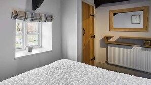 A bedroom with a large bed, a window with a view, a door, and a radiator. - Host & Stay | Mill (Consett)