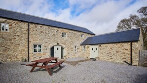 A stone building with a gravel courtyard, a picnic table, and a covered area with doors. - Host & Stay | Mill (Consett)