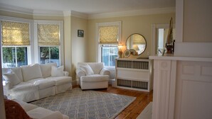 Una sala de estar con dos sofás blancos, un tapiz estampado, una chimenea y un espejo grande.