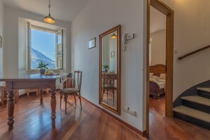 Una stanza con un tavolo da pranzo in legno, sedie, uno specchio grande e vista su una montagna attraverso una finestra.