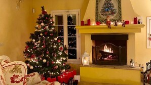 Una sala de estar acogedora con chimenea, sofás de estampado floral, un árbol de Navidad y un manto decorado para las fiestas.