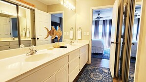 Une salle de bain d’hôtel avec un grand miroir, deux lavabos et une sculpture d’oiseau décorative.