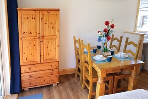 A wooden dining table with chairs, a vase with flowers, and a wooden cabinet.