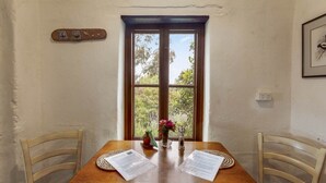 Uma mesa de jantar com papéis, um vaso de flores e uma janela com vista para o verde.