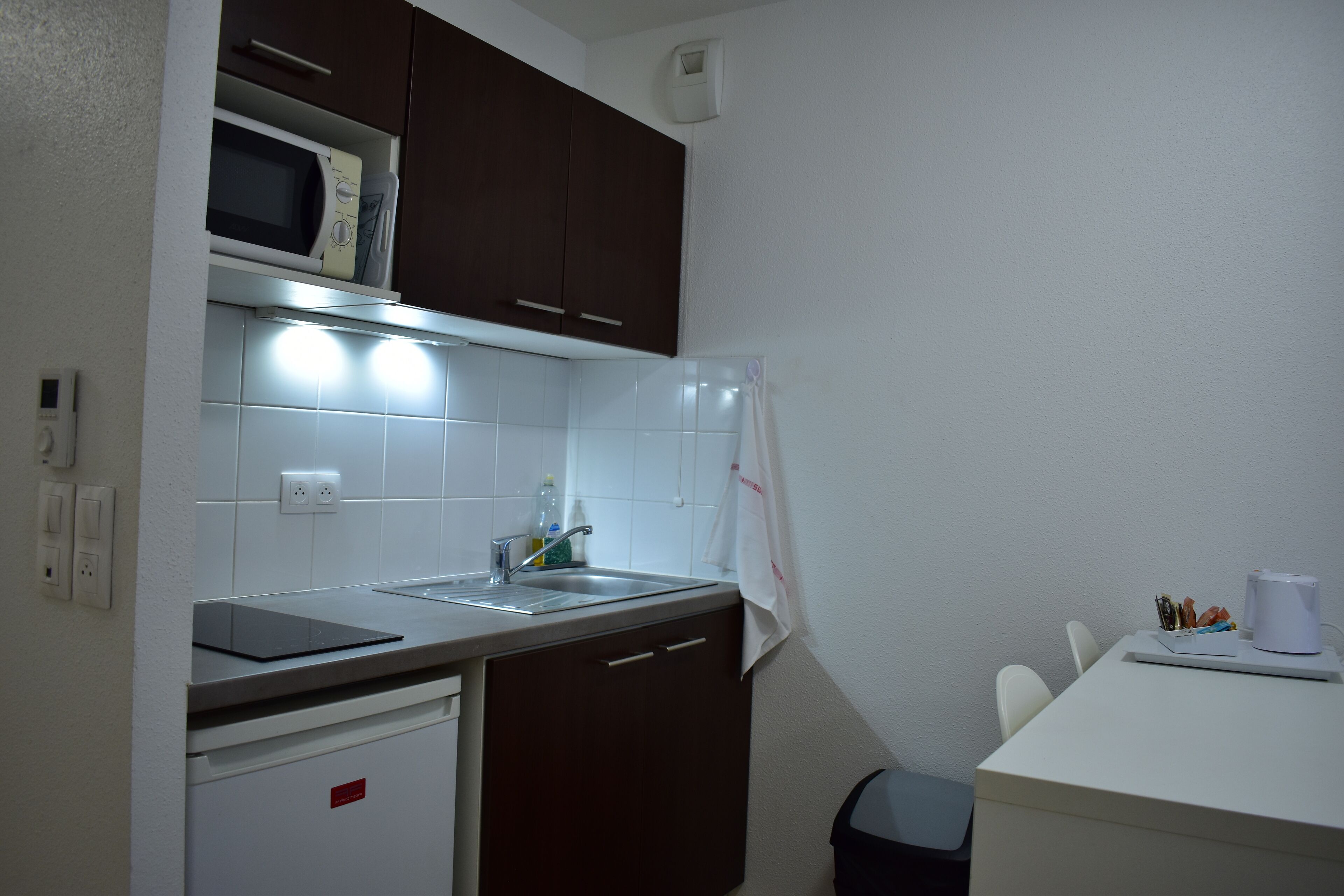 A compact kitchen with a microwave, sink, and a small refrigerator.