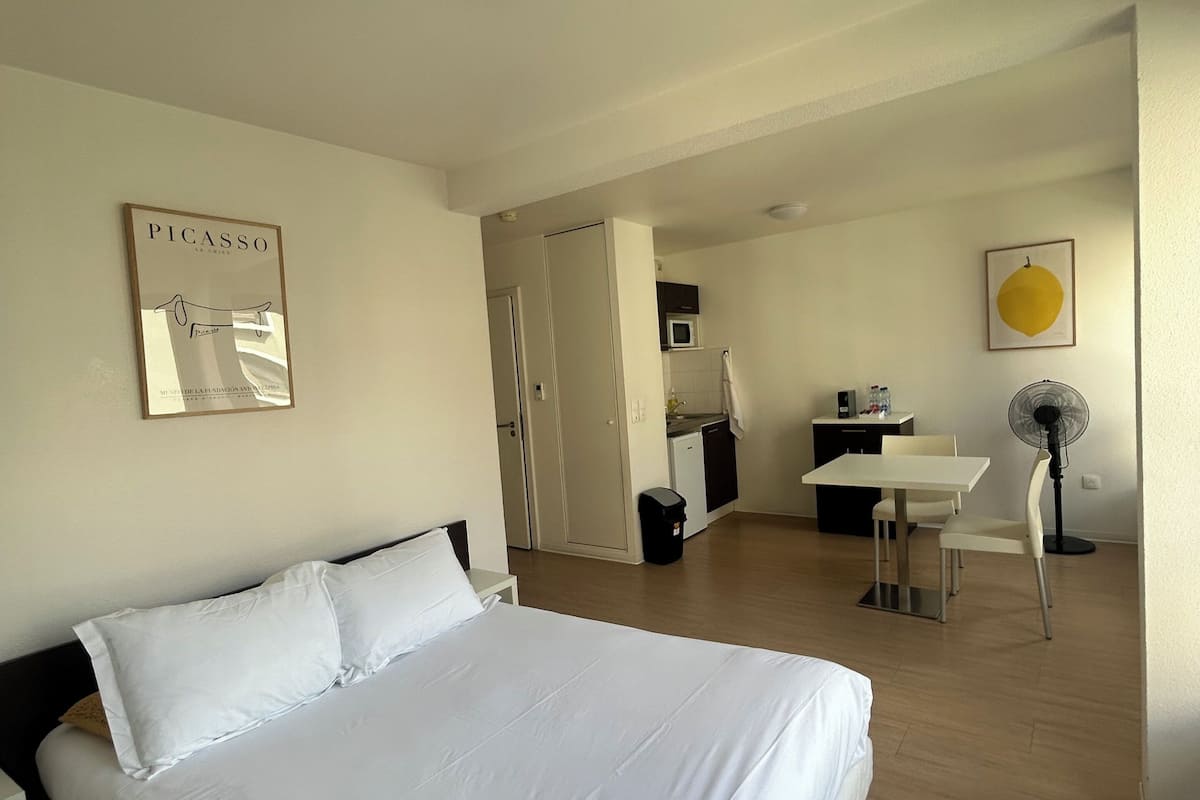 Ein Hotelzimmer mit Bett, Schreibtisch, Stuhl, Mikrowelle und Ventilator.