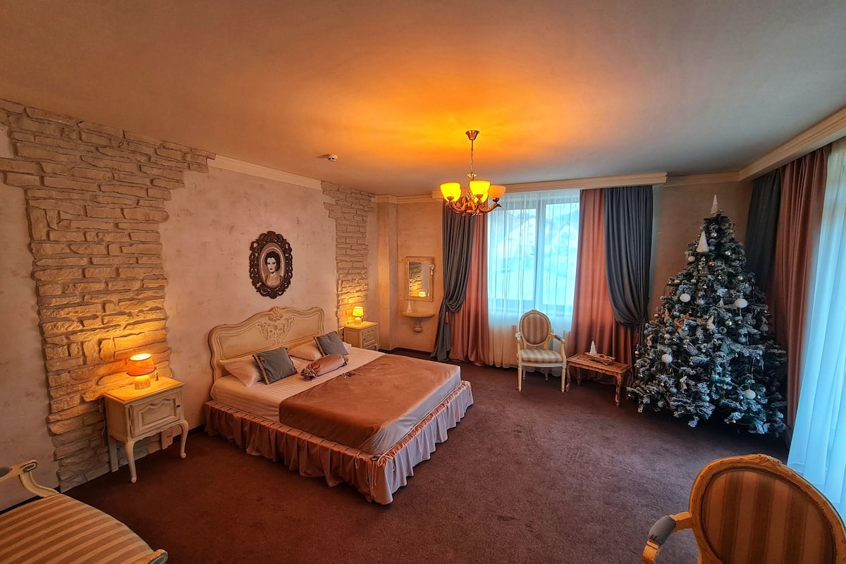 Ein Hotelzimmer mit Steinwand, einem großen Bett mit Baldachin, einem Weihnachtsbaum und einer Kristallleuchter.