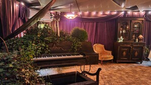 A room with a grand piano, a vintage armchair, and a dark wooden cabinet. - Vlahia Inn (Moieciu de Jos)