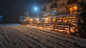 A snow-covered street with a building featuring a restaurant and a sign that reads "Cafe & Restaurant." - Vlahia Inn (Moieciu de Jos)