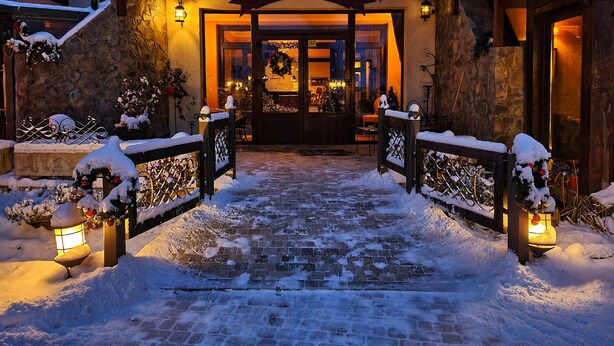 A restaurant with a stone facade, wooden entrance, and snow-covered surroundings. - Vlahia Inn (Moieciu de Jos)