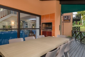 An outdoor patio with a table and chairs, a grill, and a view of the interior. - San Lameer Villa 1935 (Southbroom)