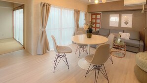 A modern living room with a round dining table, two chairs, a sofa, and a small side table. - Staypia Condominium Namba Ebisu (Osaka)