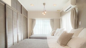 A bedroom with two beds, a ceiling light fixture, and an air conditioning unit. - Staypia Condominium Namba Ebisu (Osaka)