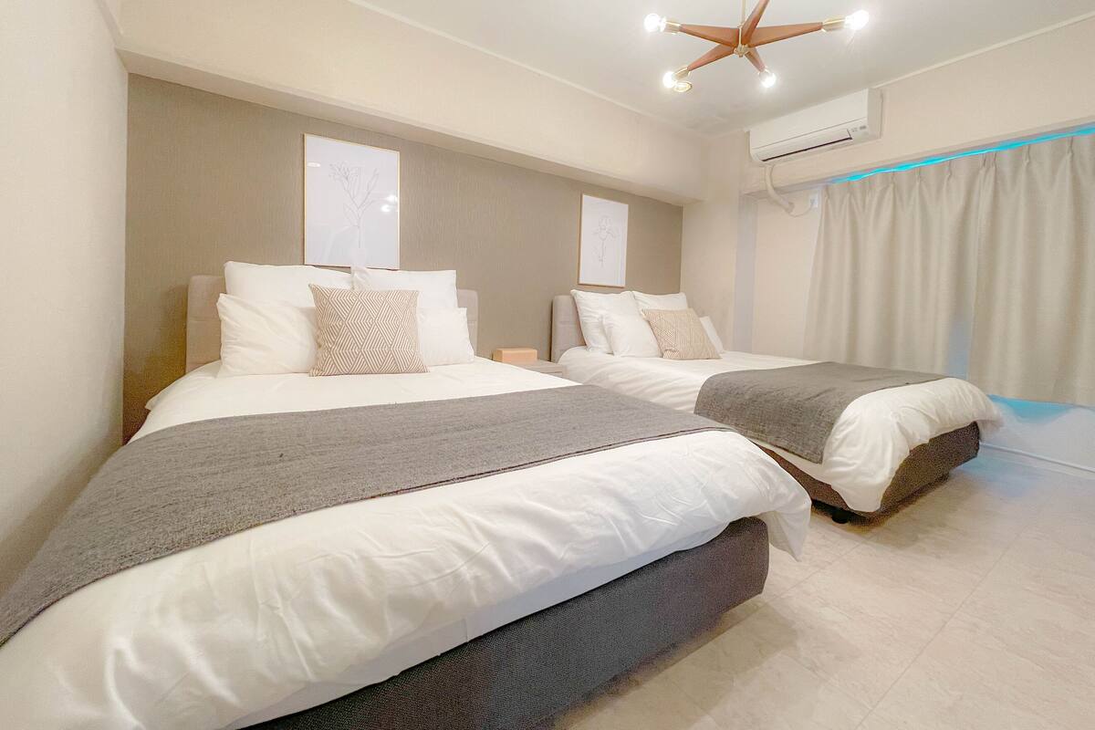 A hotel room with two beds, a ceiling fan, and an air conditioning unit.