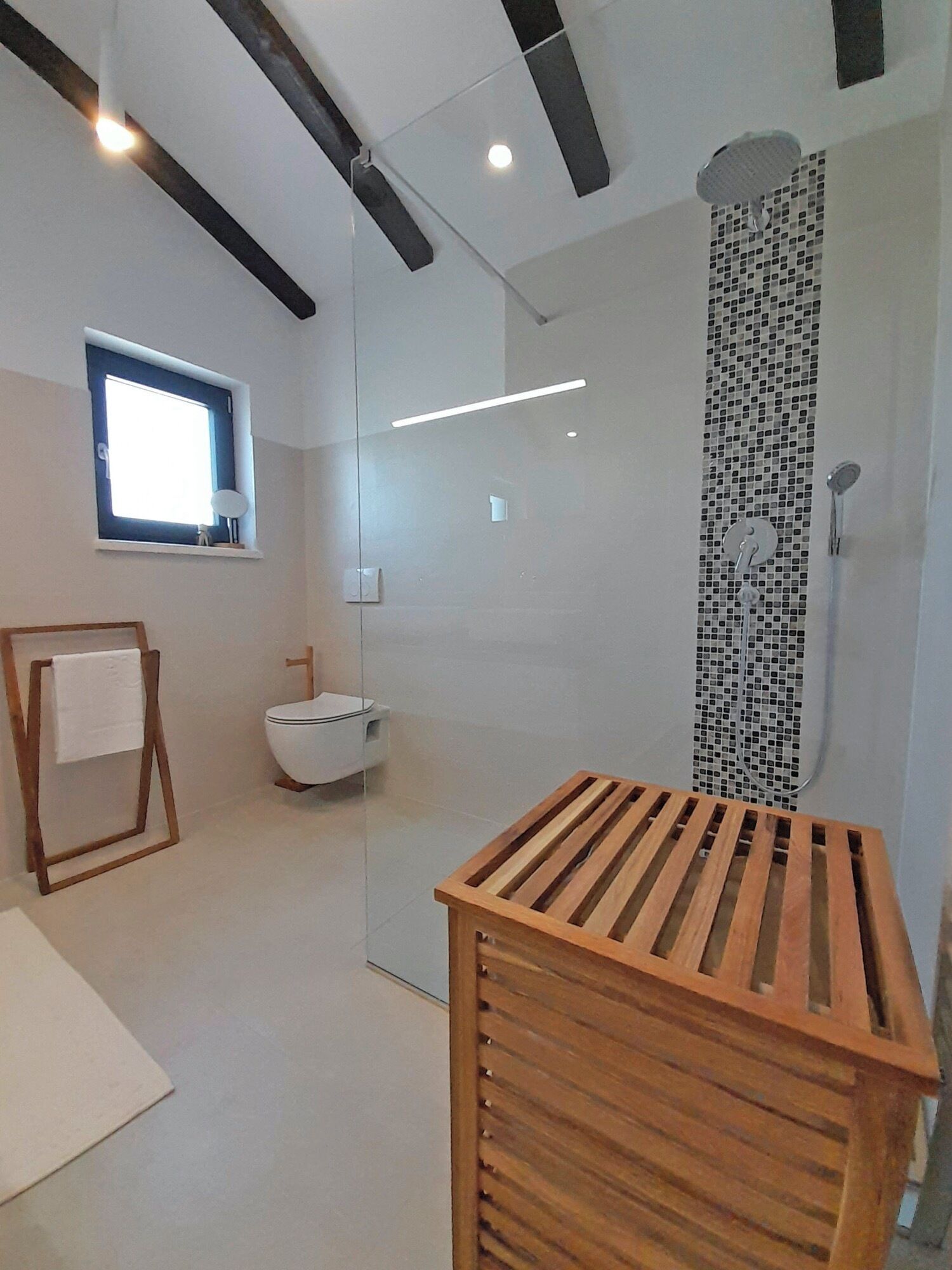 Ein modernes Badezimmer mit einer gläsernen Duschkabine, einem Holzbadezimmer-Möbel und einem Fenster.