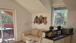 A modern, open-plan living and dining area with a loft-style ceiling, a sofa set, a kitchen counter, and a view through a large window. - Sea view apartament Blue Star (Sv. Filip I Jakov)