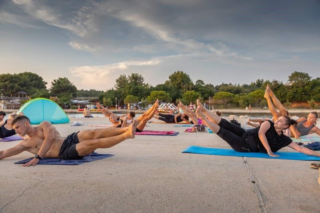 Un grupo de personas realizando un ejercicio de yoga sobre una superficie de hormigón al aire libre.