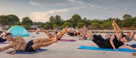 Un grupo de personas realizando un ejercicio de yoga sobre una superficie de hormigón al aire libre.