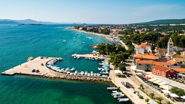 An aerial view of a coastal town with a marina, boats, and buildings along the waterfront. - Sea view apartament Blue Star (Sv. Filip I Jakov)