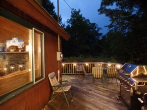 A wooden deck with outdoor seating and a barbecue grill.