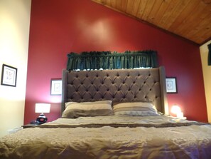 A bedroom with a tufted headboard, a bed with patterned bedding, and two bedside lamps.