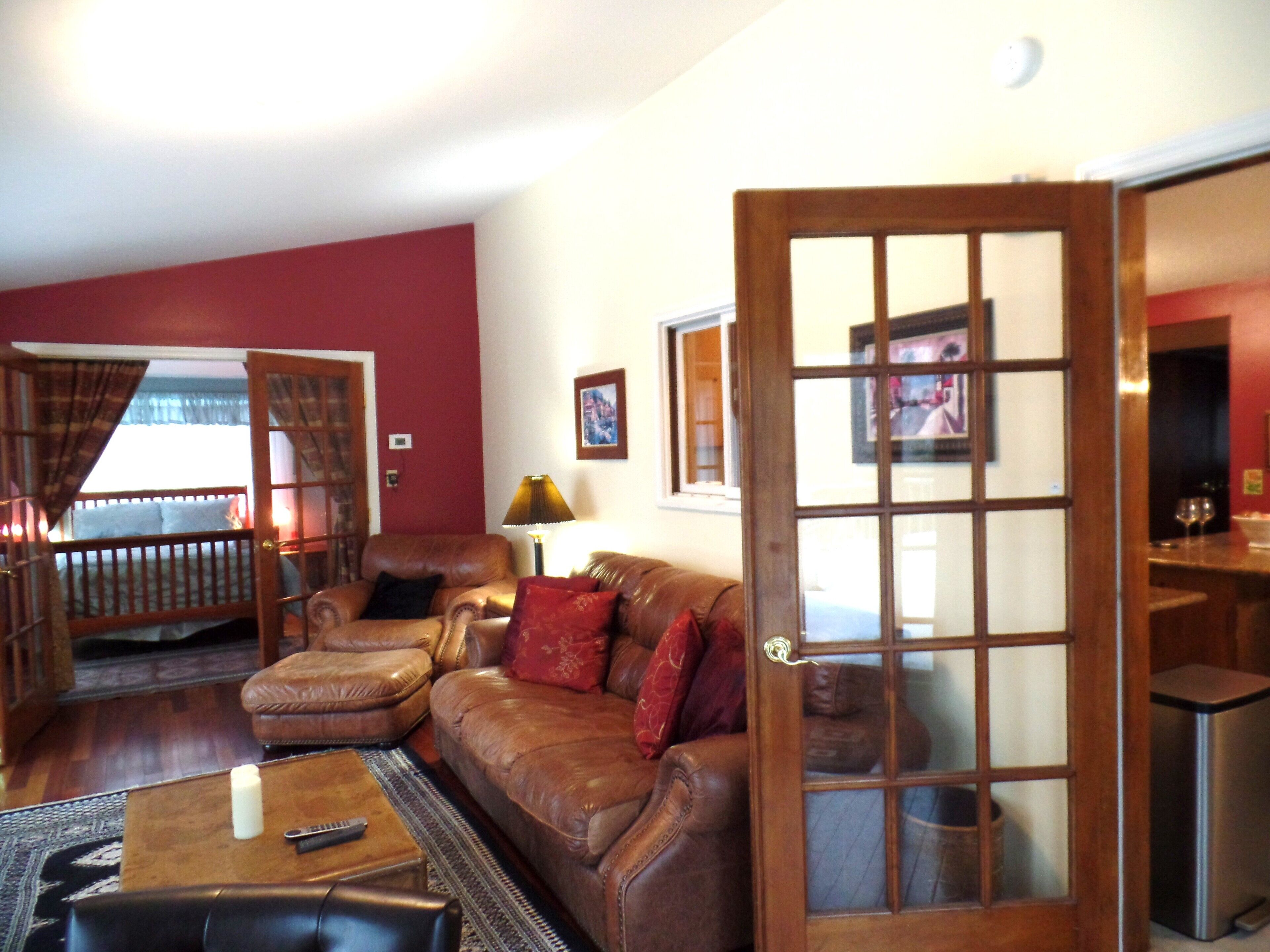 A living room with a brown leather sofa, a wooden coffee table, a lamp, and a door with glass panels.