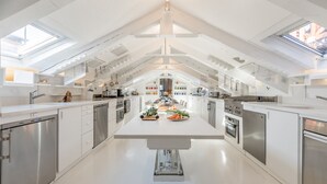 Une cuisine moderne dotée de fenêtres de toit, d’appareils électroménagers en acier inoxydable et d’un îlot central où sont disposés des produits frais.