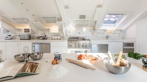 Une cuisine moderne avec des meubles blancs, un four encastré et une lucarne.