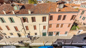 Un bâtiment situé au bord du canal, avec un toit en tuiles, un quai où sont amarrés des bateaux et une promenade piétonne.