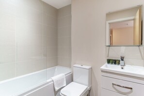 Bathroom features a white bathtub, toilet, and sink with mirror.