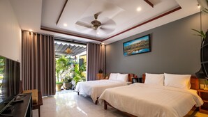 A hotel room with two beds, a TV, a desk, and a ceiling fan. - Hoi An Town Center (Da Nang)