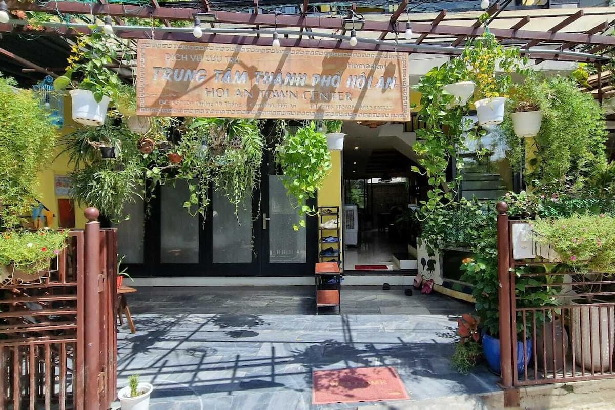 A covered entrance with a sign, potted plants, and a metal gate.