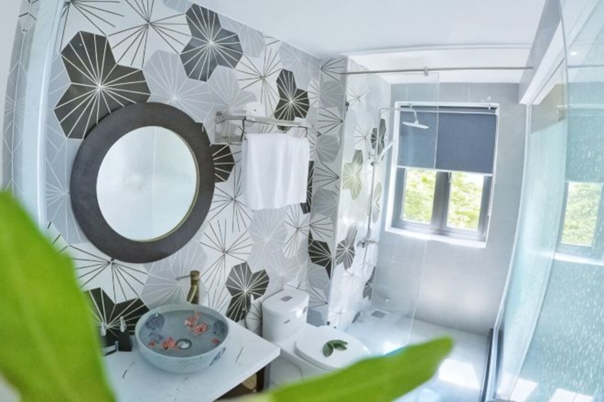 A bathroom with a large mirror, a sink, a toilet, and a shower area.