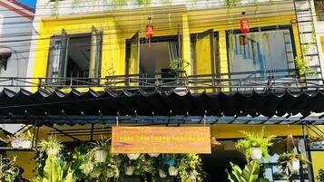 A two-story building with balconies, potted plants, and a sign indicating a hotel.