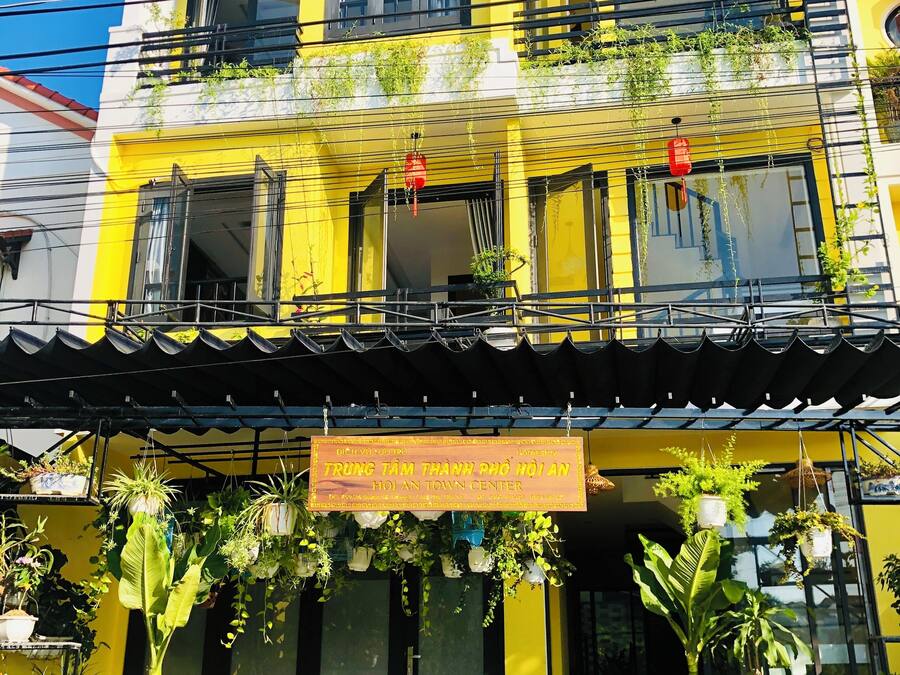 A two-story building with balconies, potted plants, and a sign indicating a hotel.