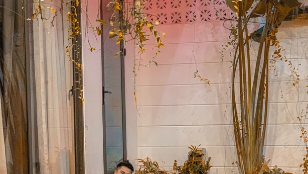 A man and a woman in a swimming pool with a decorative wall and plants in the background. - Hoi An Town Center (Da Nang)
