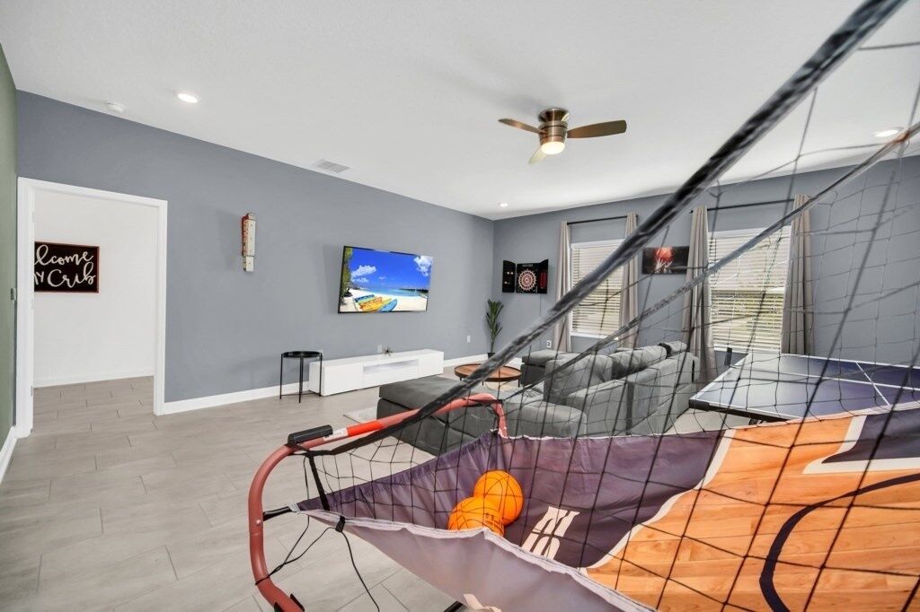 A living room with a basketball hoop, a TV, and a 'Welcome' sign.